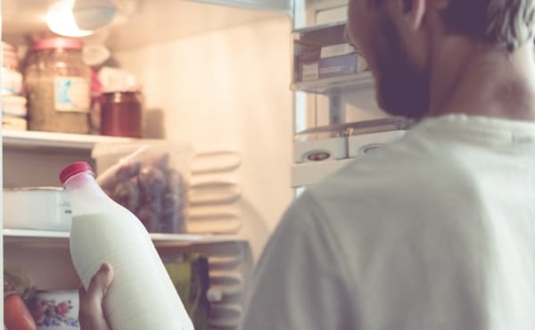 Photo d'un homme sortant du lait de son frigo
