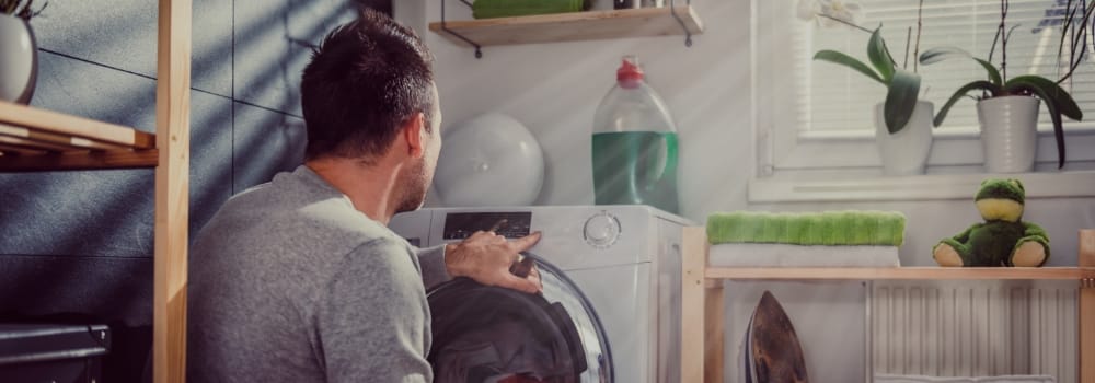 Photo d'un homme dans sa buanderie face à la machine à laver
