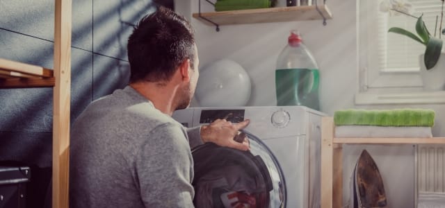 Photo d'un homme dans sa buanderie face à la machine à laver