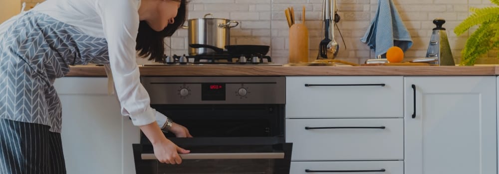 Photo d'une femme qui met quelque chose dans le four