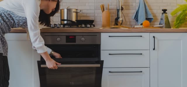 Photo d'une femme qui met quelque chose dans le four